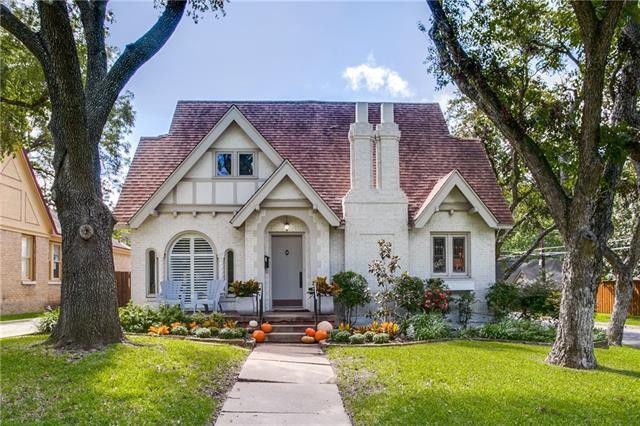 White Tudor-style cottage in a Dallas/Fort Worth neighborhood under big oak trees
